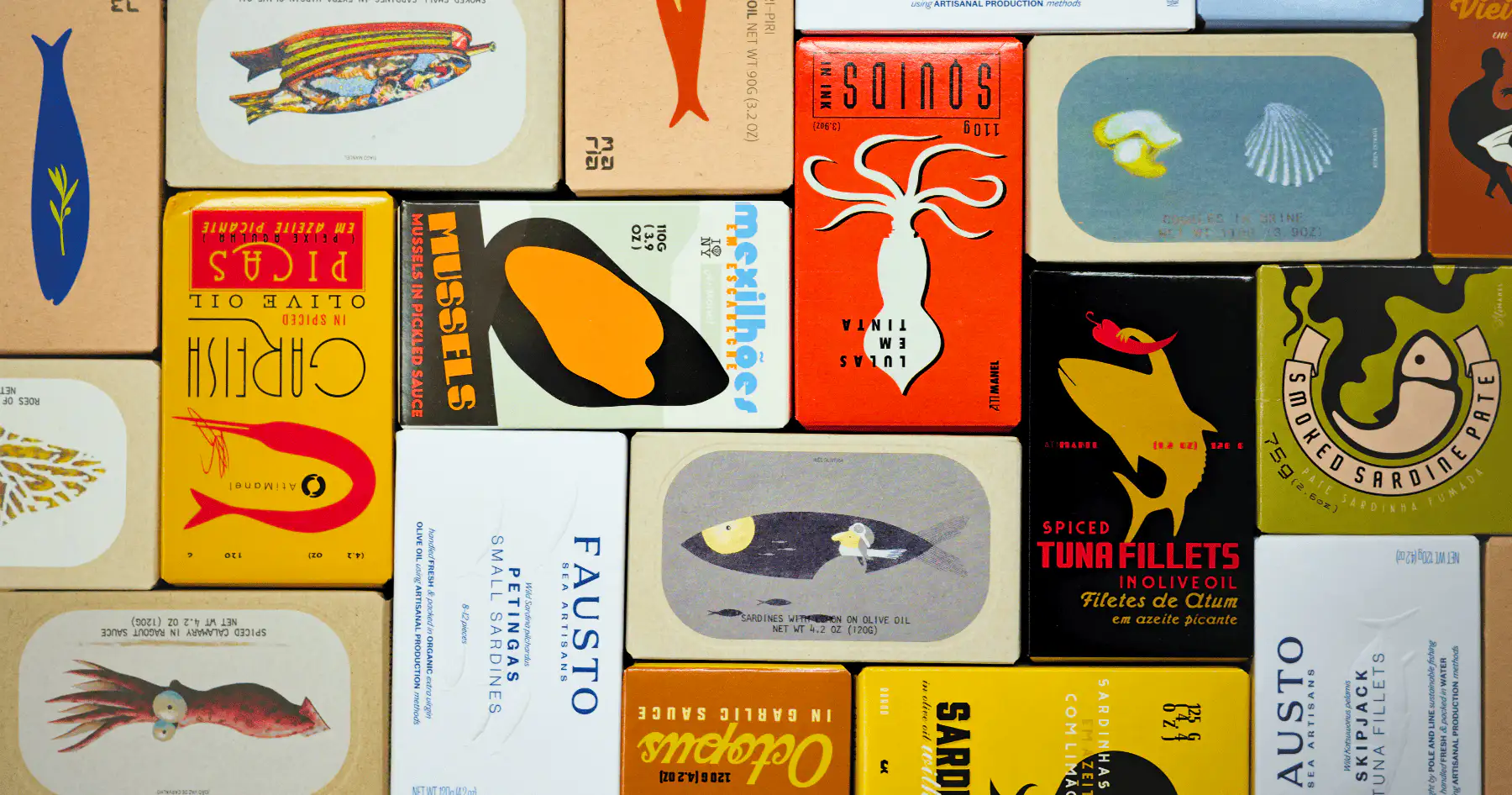 Verschillende soorten vis in blik uitgestald op een houten plank