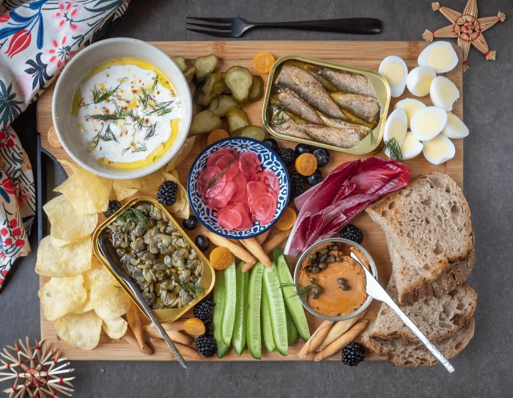 Nordic-style aperoplank met Scandinavische vis in blik, gepekelde radijsjes en zure room