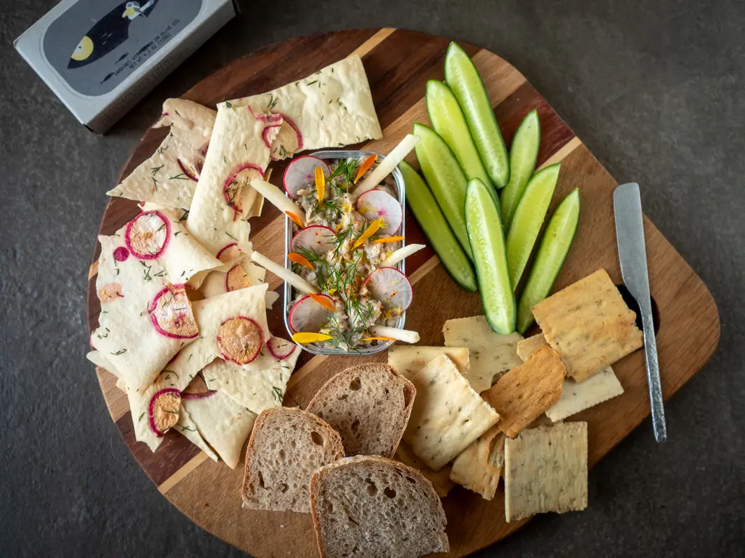 Rilettes van sardines geserveerd in een blikje, gegarneerd met appelstaafjes, radijs en verse dille